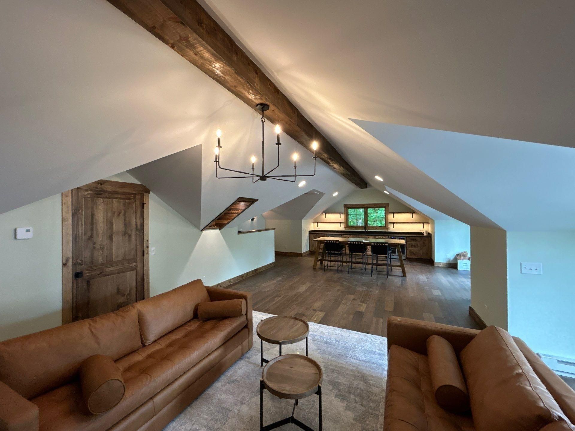 Open-plan kitchen and living area with dark wood floors, large windows, and stone fireplace