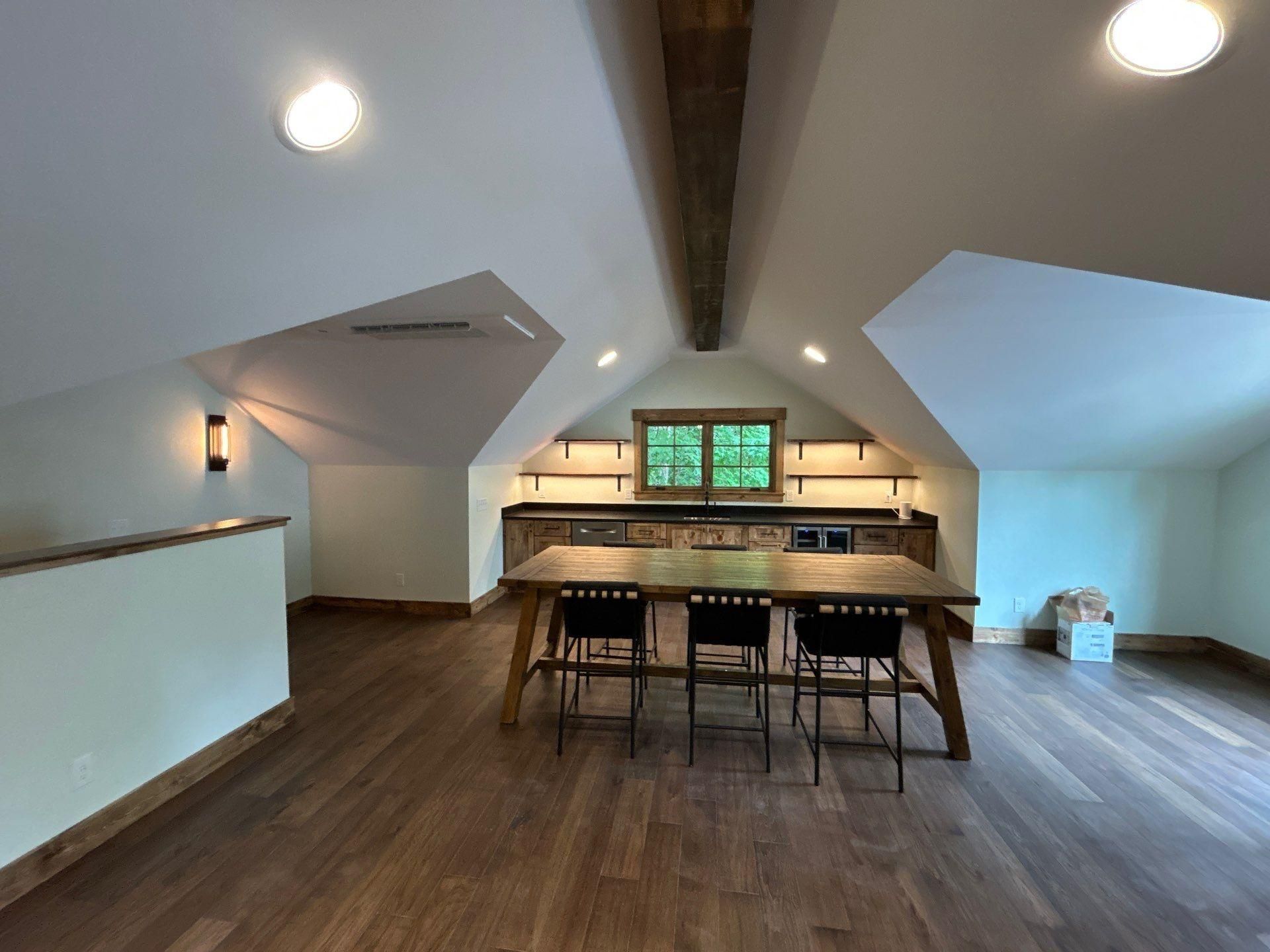 Empty living room with wood floors, white walls, vaulted ceiling, and a fireplace by large windows