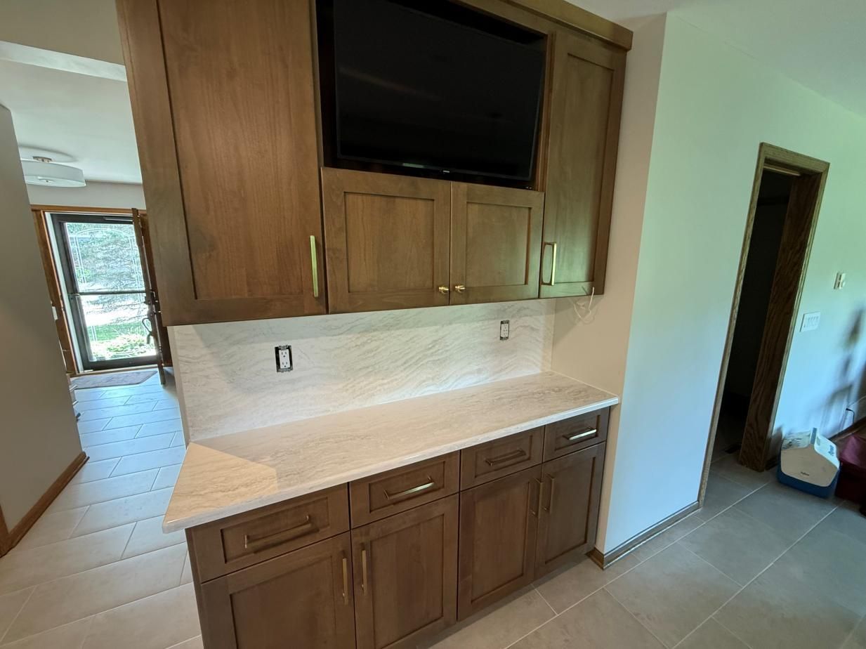 Empty kitchen nook with wood cabinets, white countertops, and beige tile flooring
