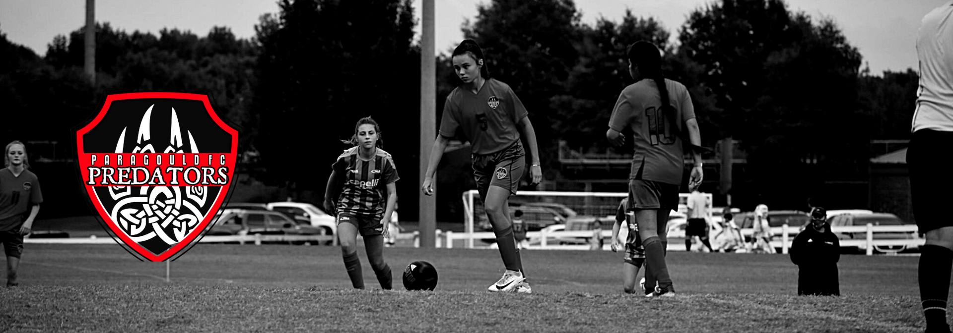 Soccer players on a field during a match, with a red-and-white team logo overlay on the left