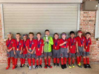 Group of scouts in red uniforms posing for a team photo in front of a closed garage door
