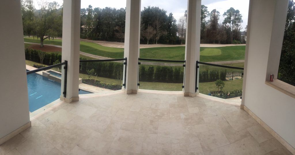 an empty balcony with glass rails with a view of a golf course
