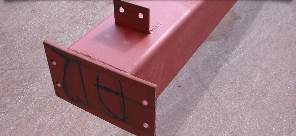 A red metal beam is sitting on a concrete surface.