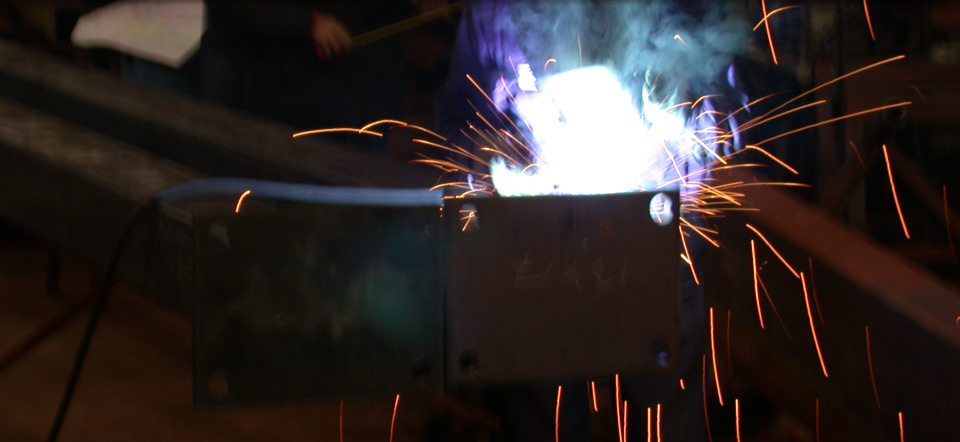 A person is welding a piece of metal with sparks coming out of it.