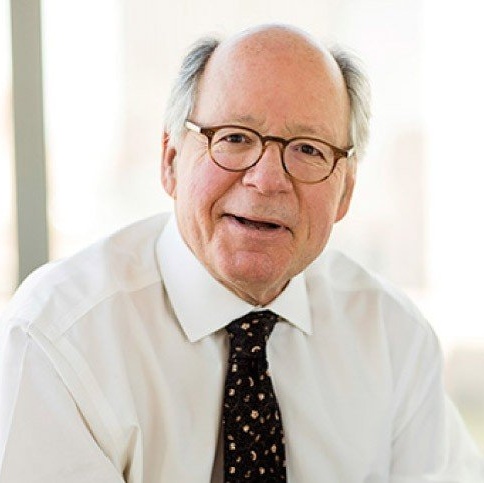 A bald man wearing glasses and a tie is smiling for the camera.