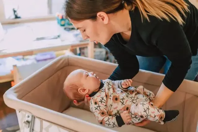Mother safely placing baby in crib during blended parenting assessment at home