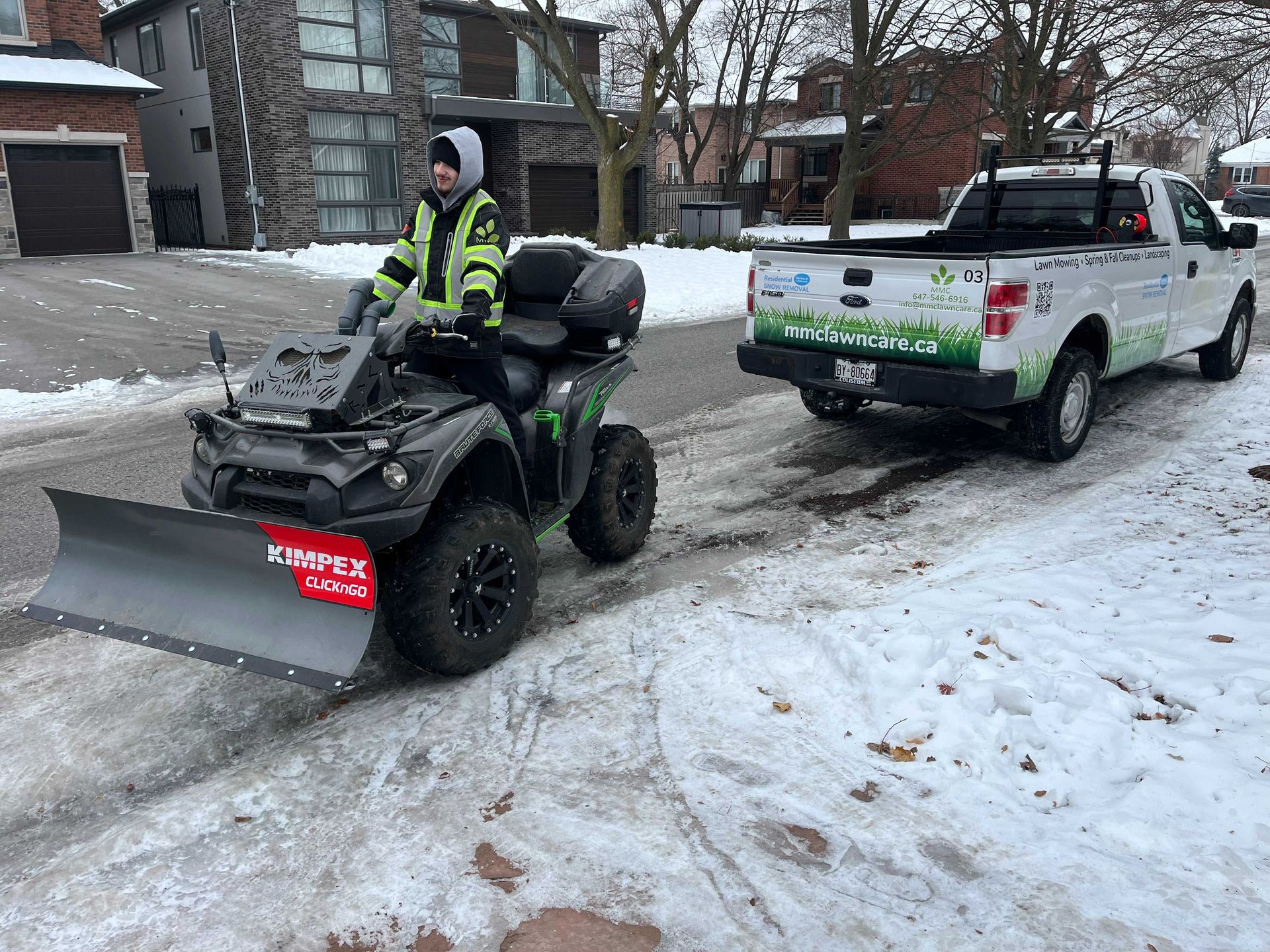 A person on a snow-plowing ATV and a truck on a snow-covered residential street.