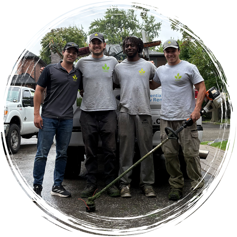 Four workers in gray shirts pose outdoors holding a long tool, with trucks and trees in the background.