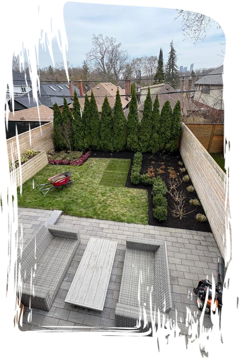 Backyard patio with lawn furniture, garden beds, and trees.