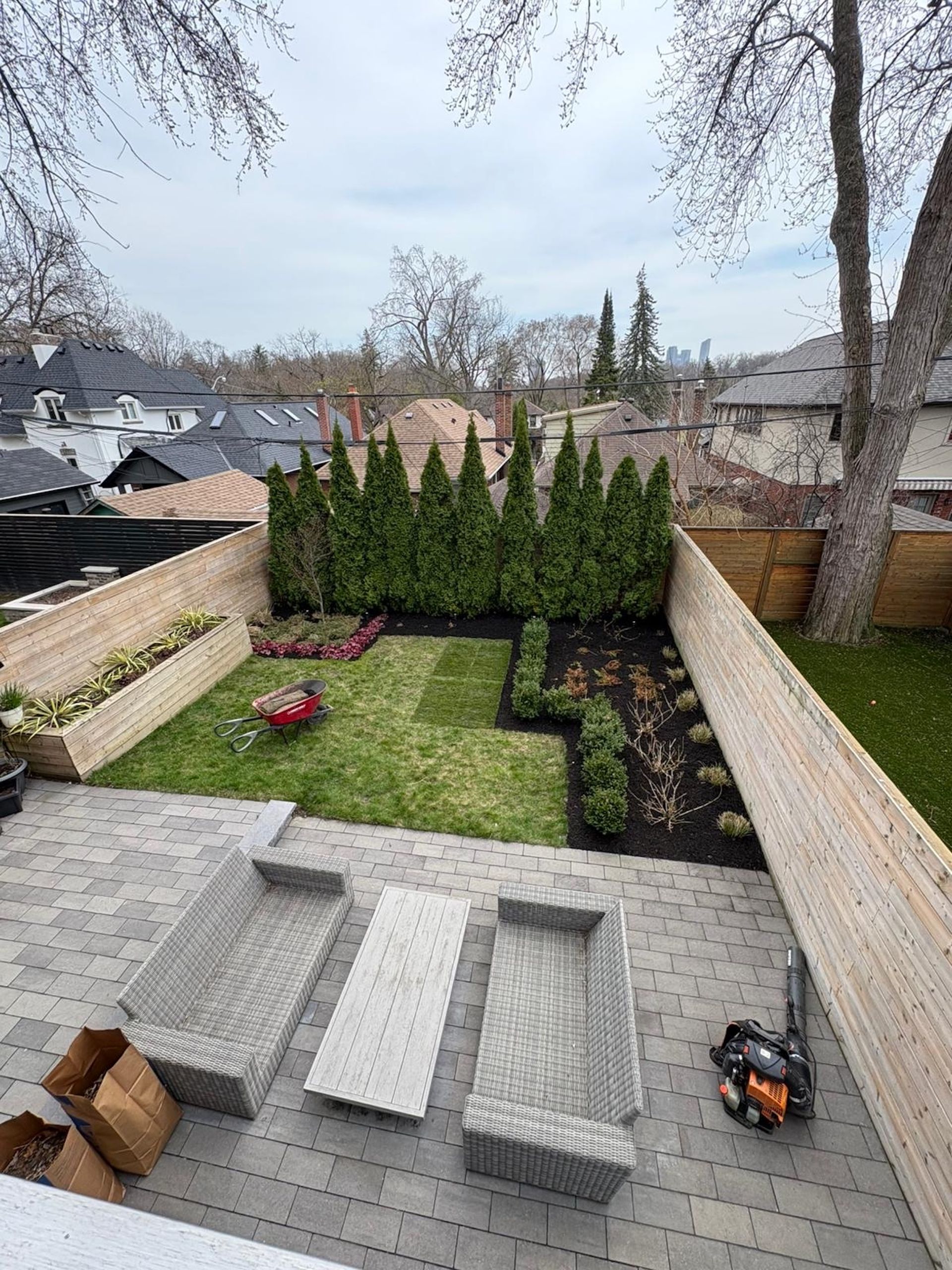 Backyard patio with lounge chairs, grass, shrubs, and brick walls.