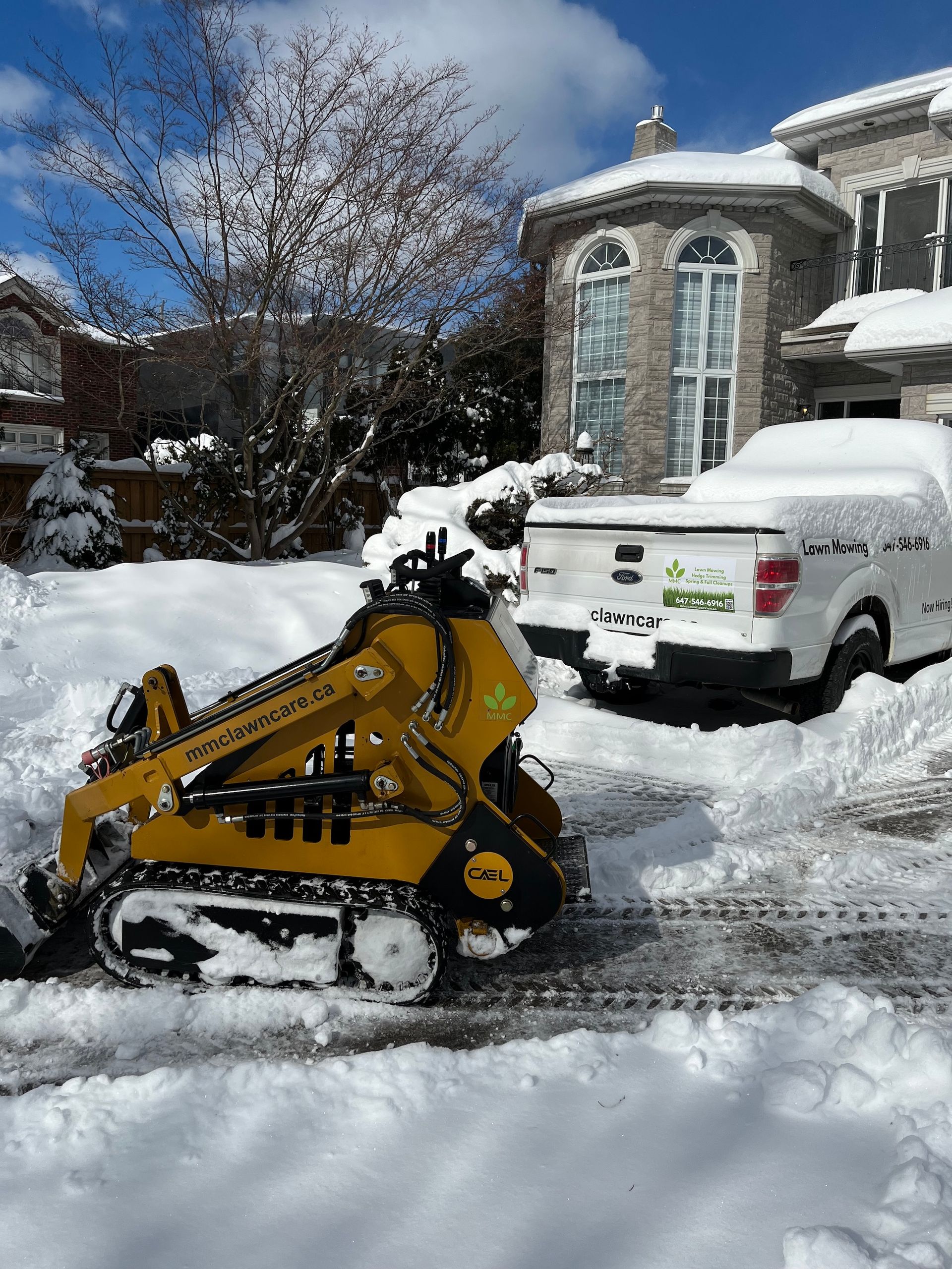 Yellow snowplow clearing snow from a driveway.