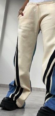 A person wearing a pair of white sweatpants with black stripes on the side.
