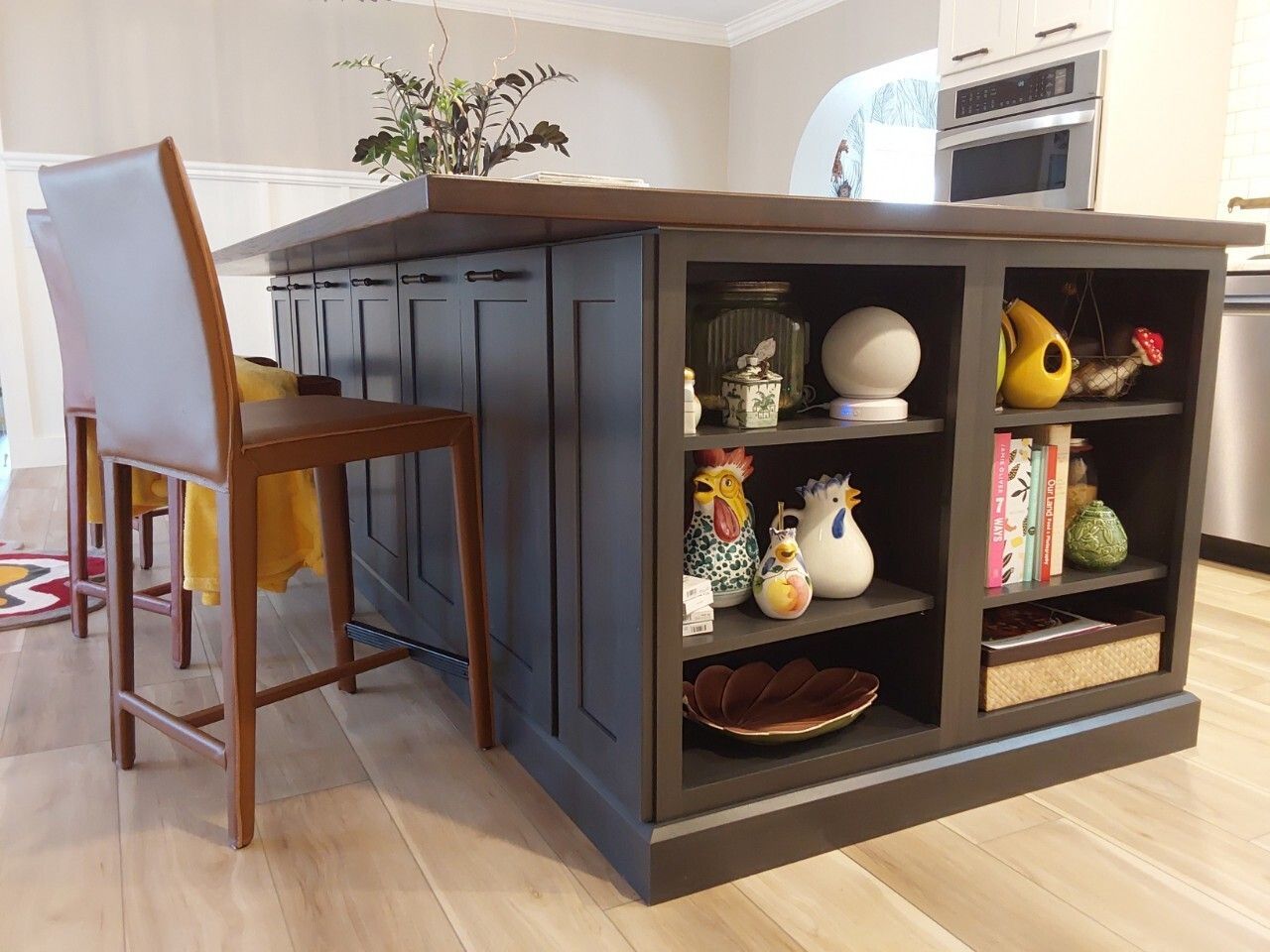 Closeup of open shelving on end of elegant navy blue island cabinetry with solid wood countertop.