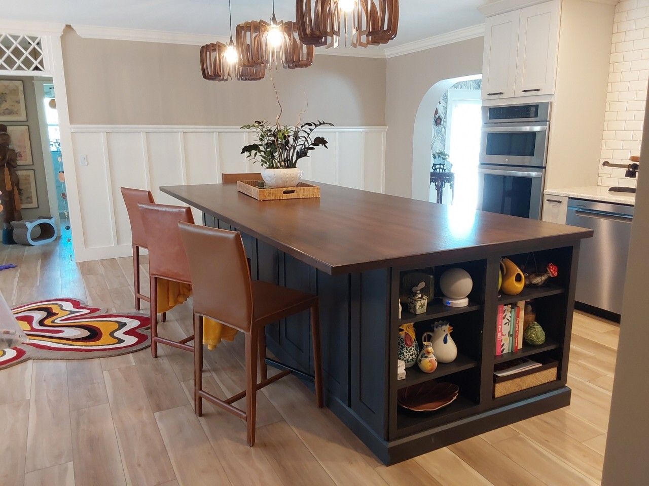 Open shelving on end of elegant navy blue island cabinetry with solid wood countertop.
