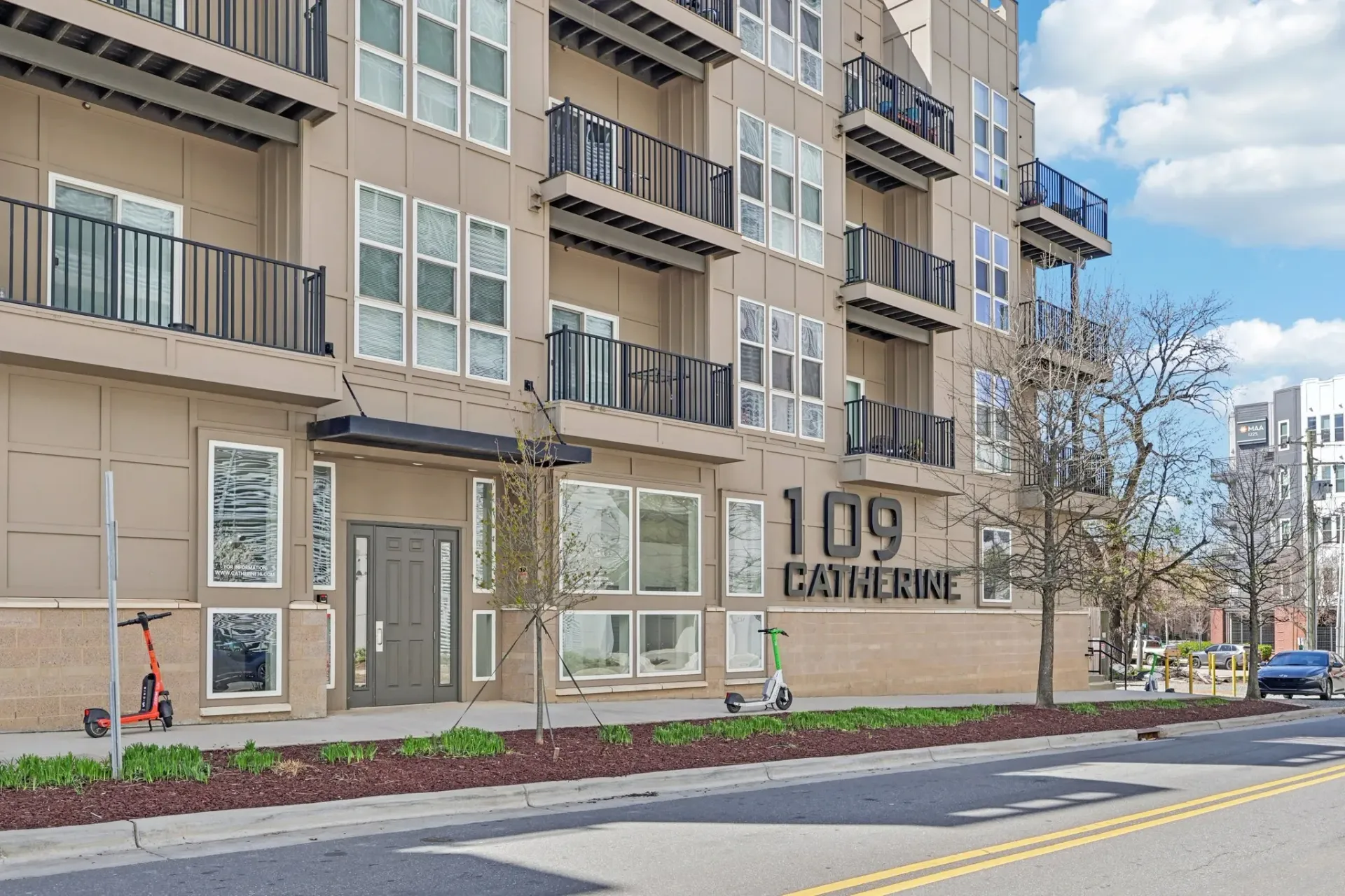 Exterior of the 109 Catherine apartment building with signage and scooters at Catherine 36 Apartments for rent in Charlotte, NC.