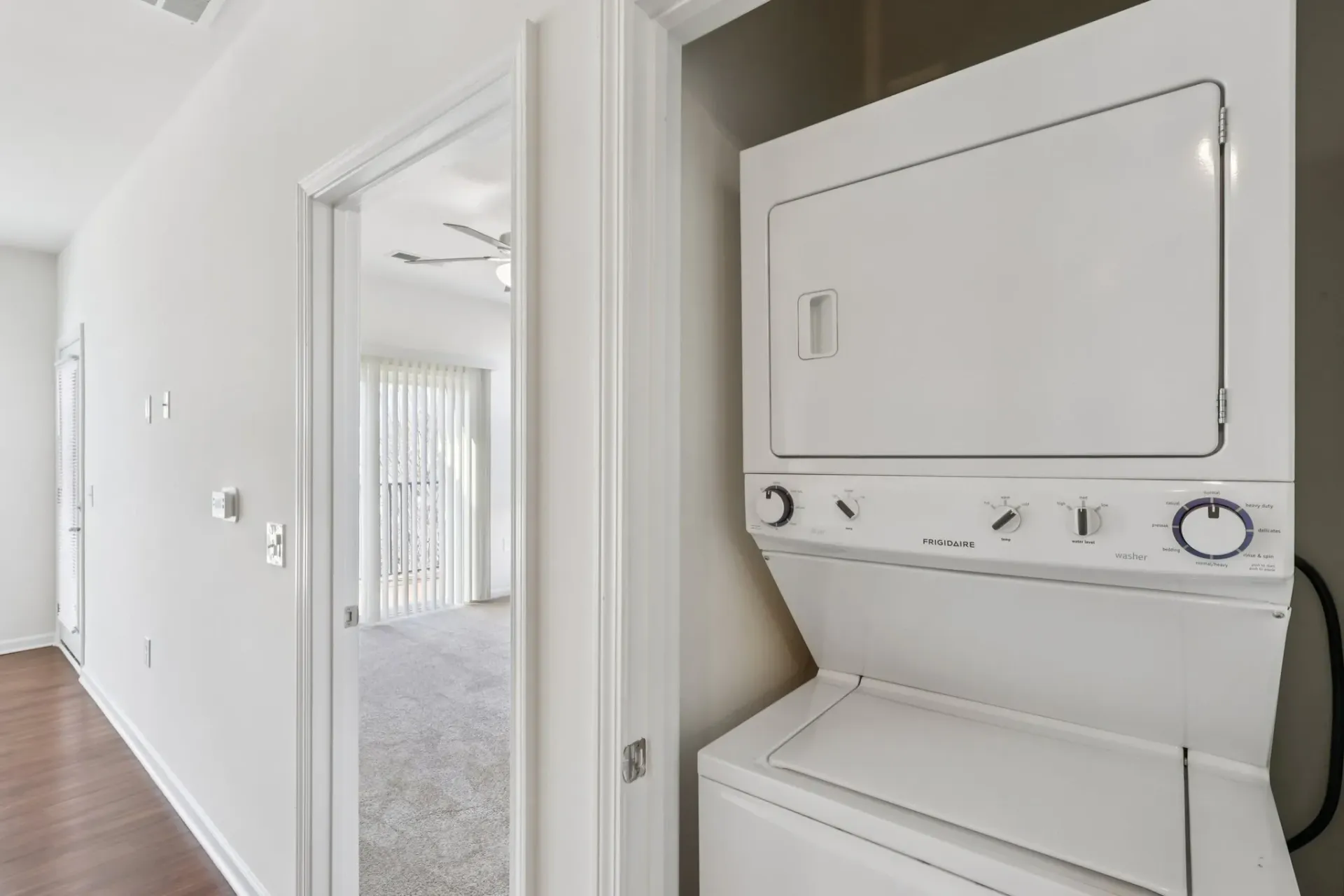 Stackable washer and dryer in a hallway with a bedroom visible through an open door at Catherine 36 Apartments for rent in Charlotte, NC