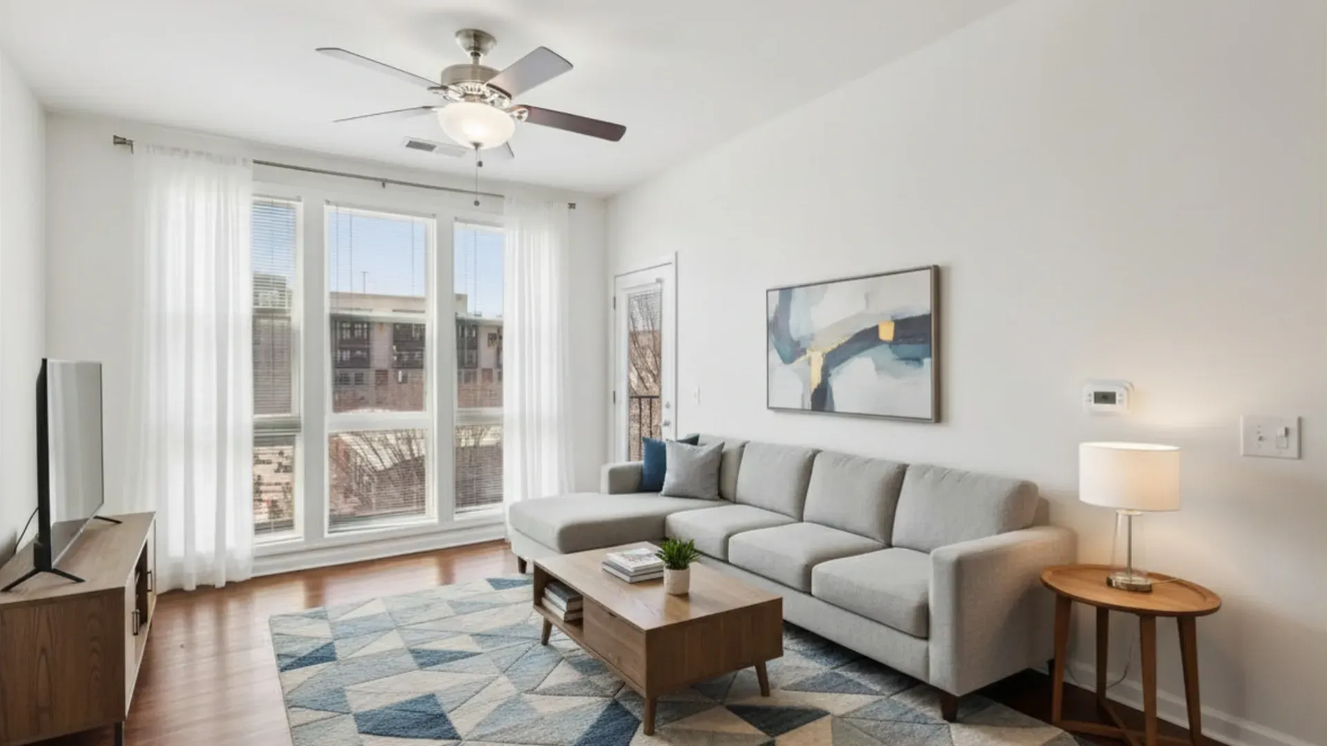 Bright living room with a sectional sofa, coffee table, TV, and large windows at Catherine 36 Apartments for rent in Charlotte, NC