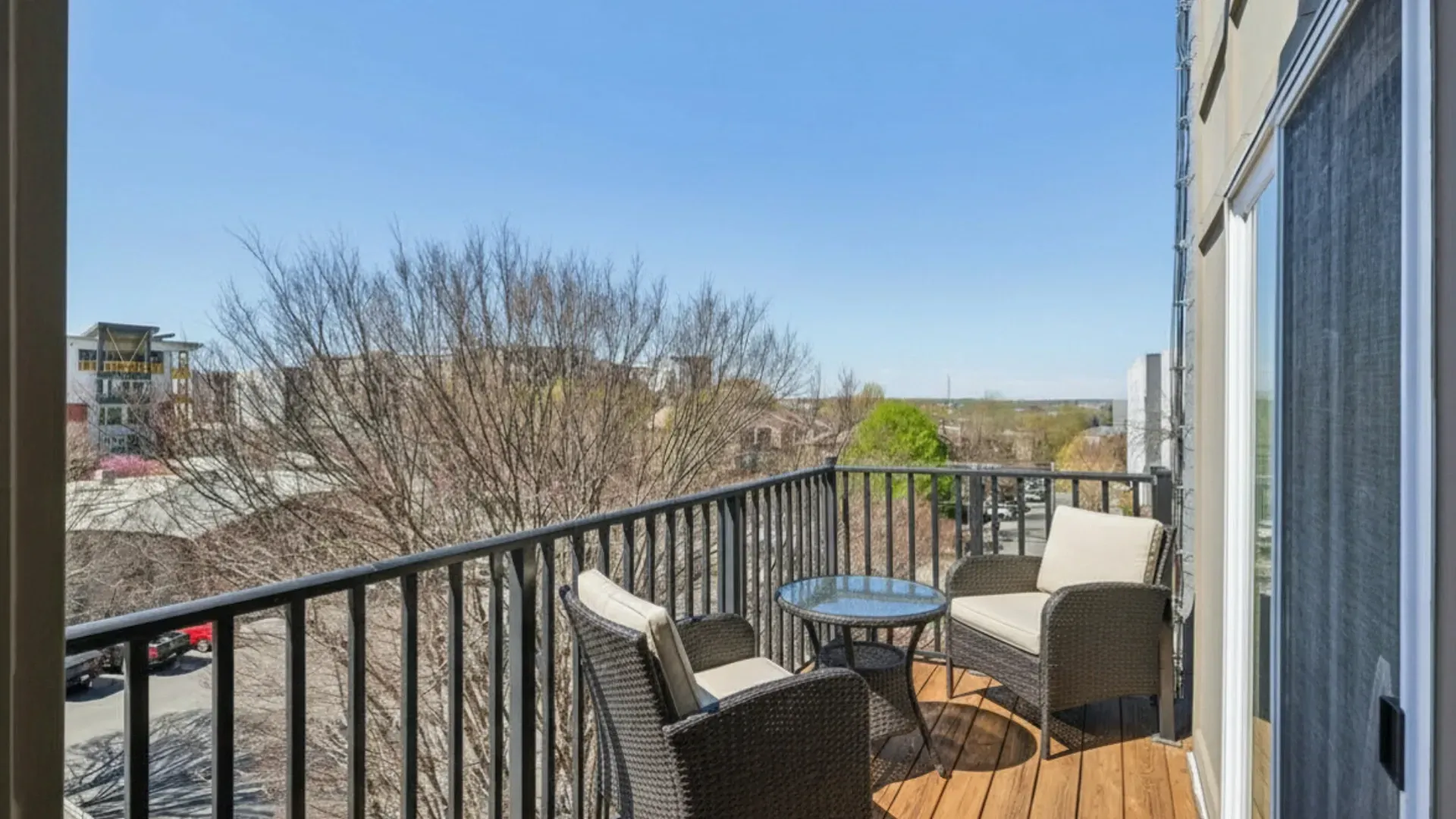 Balcony with two chairs, a small table, and a view of the city at Catherine 36 Apartments for rent in Charlotte, NC.