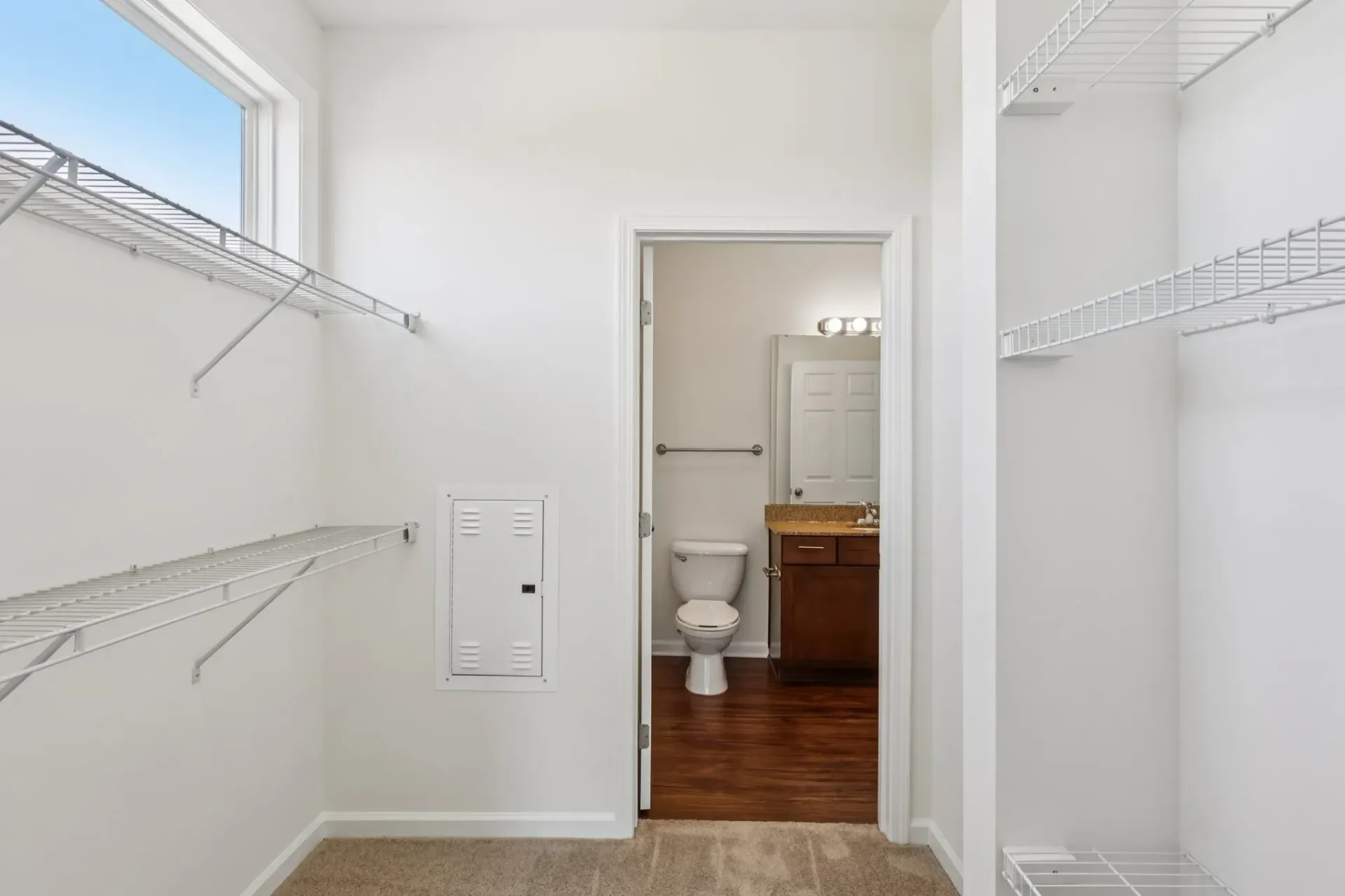Walk-in closet with built-in shelves and a view into the bathroom with toilet and vanity at Catherine 36 Apartments for rent in Charlotte, NC