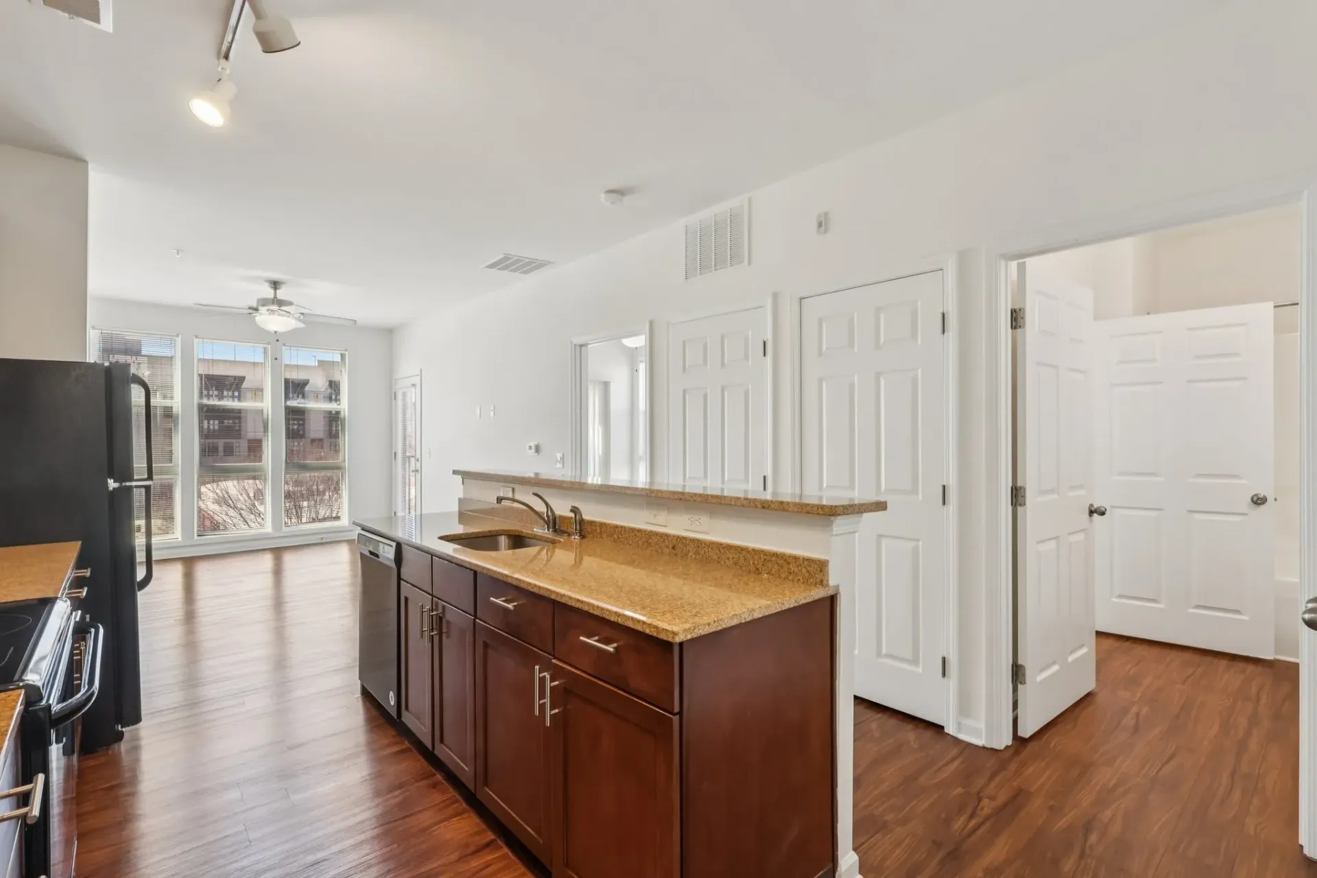 Modern kitchen with dark wood cabinets and granite countertops, open to living area at Catherine 36 Apartments for rent in Charlotte, NC