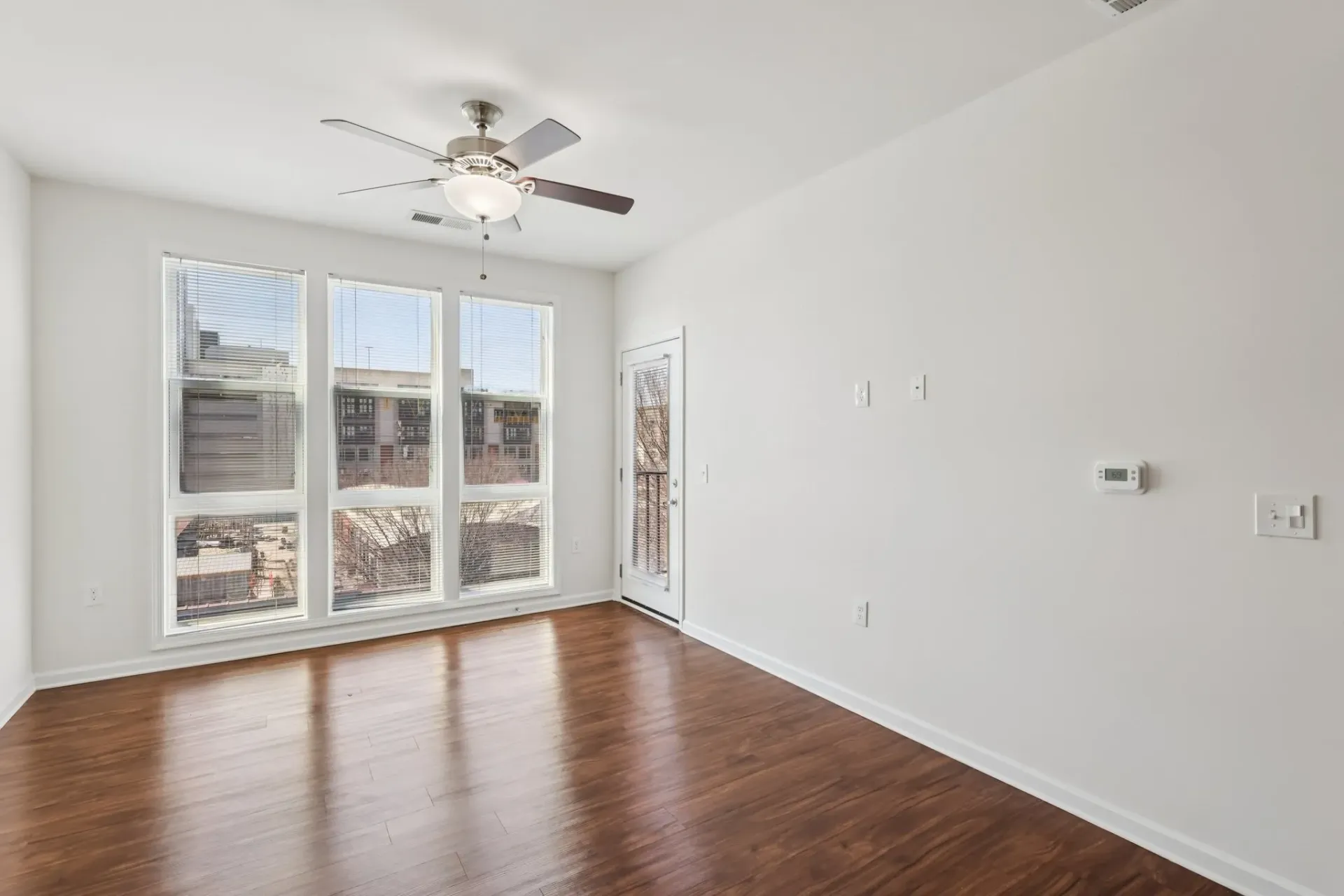 Living room with hardwood floors, large windows, and a ceiling fan at Catherine 36 Apartments for rent in Charlotte, NC