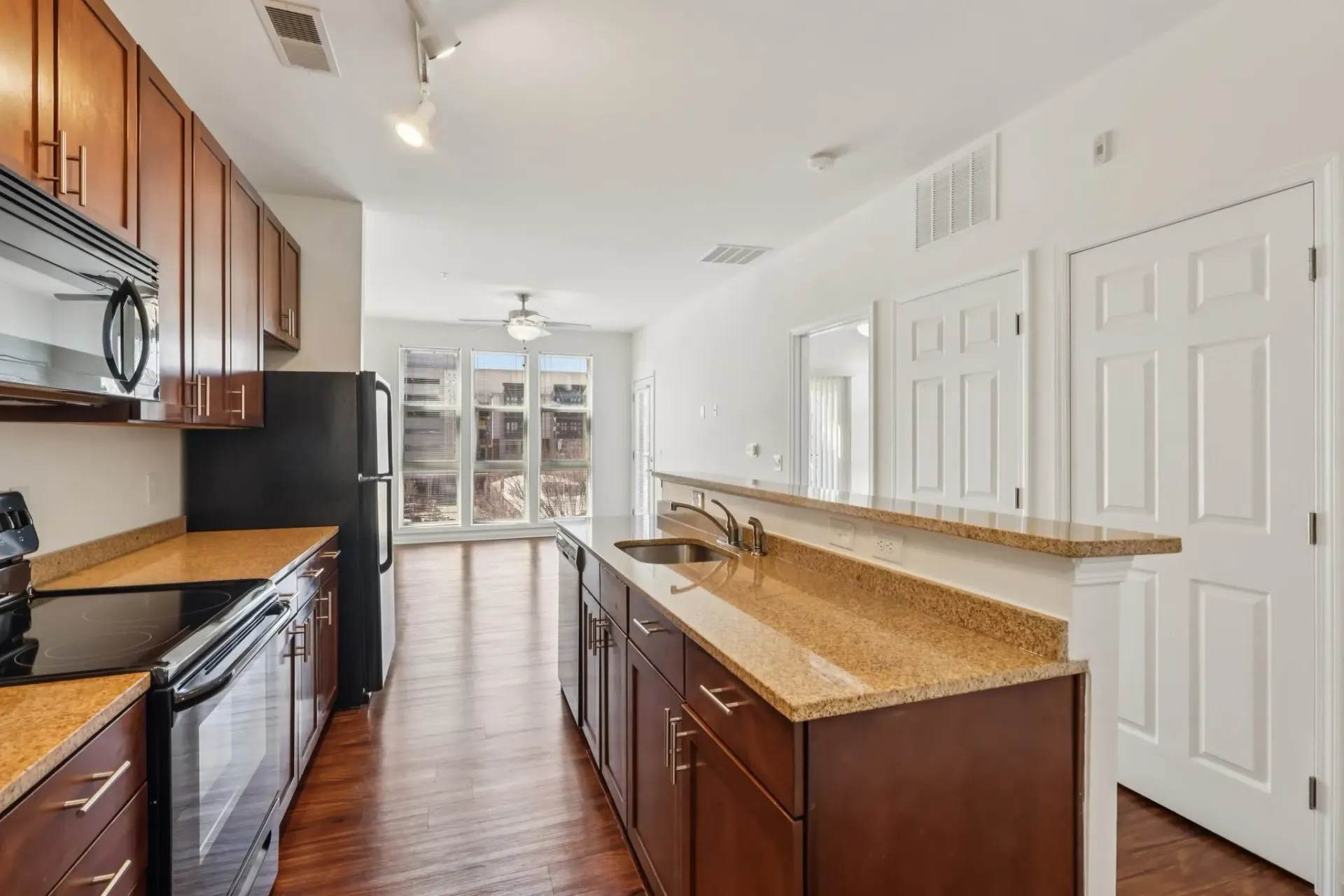 Modern kitchen with dark wood cabinets, granite countertops, and stainless steel appliances at Catherine 36 Apartments for rent in Charlotte, NC