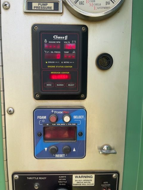 Close-up of industrial control panel with gauges, lit display, and blue button section.