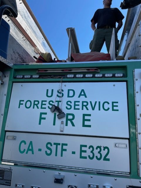 USDA Forest Service fire truck with a person standing on top near the front cab