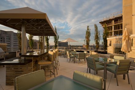A patio with tables , chairs , umbrellas and a bar.