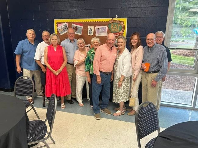 A group of people posing for a picture with one man wearing a name tag