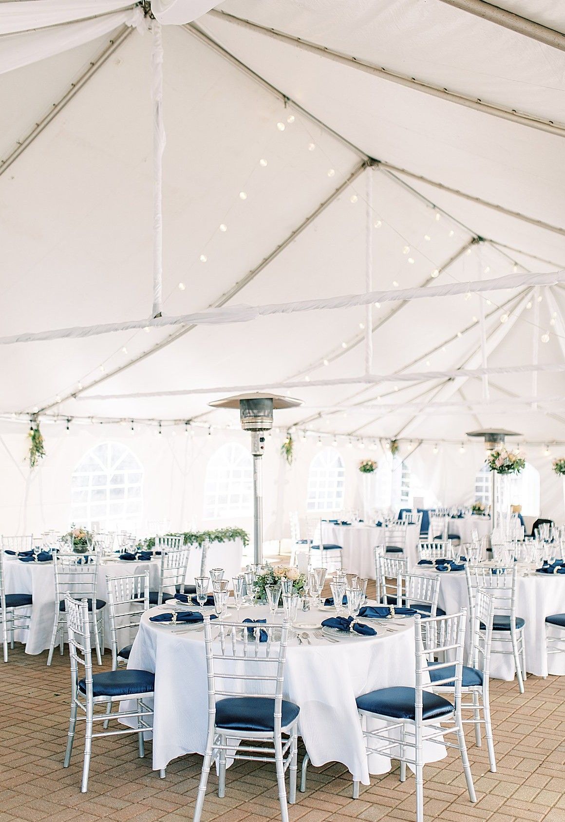 A large white tent with tables and chairs set up for a wedding reception.