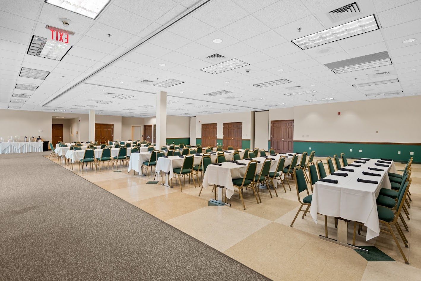 A large room with tables and chairs and an exit sign