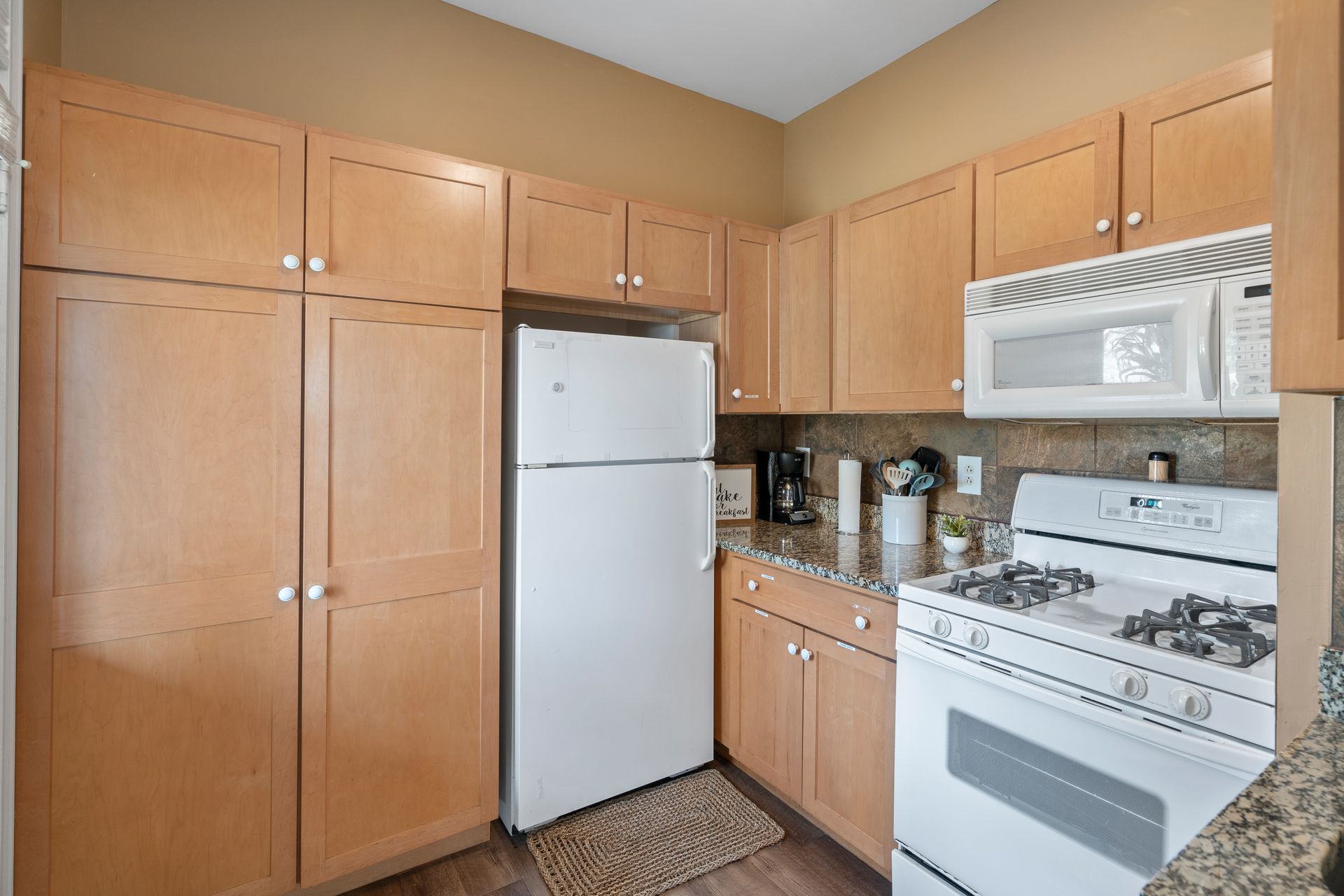 A kitchen with a refrigerator , stove , microwave and cabinets.