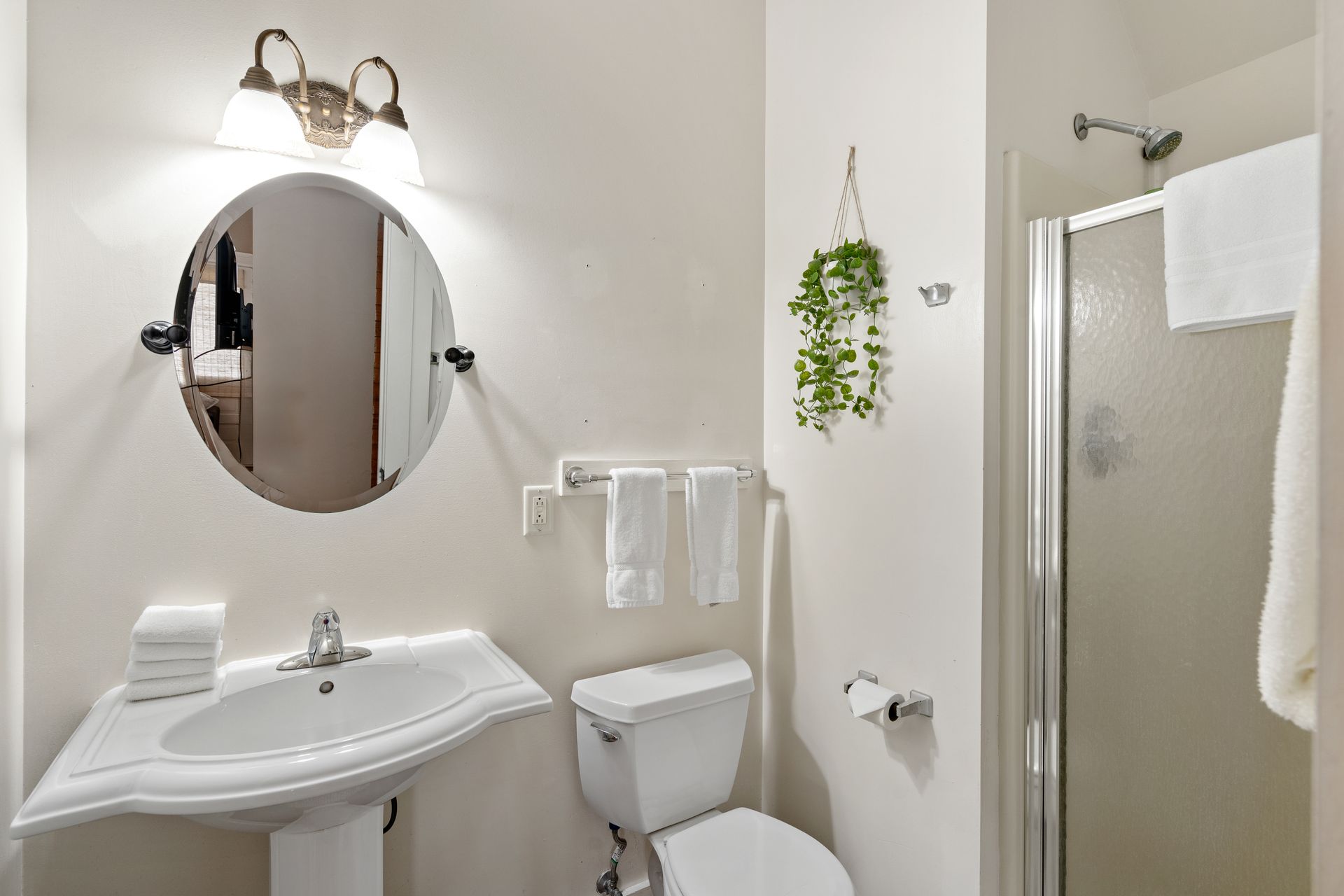A bathroom with a toilet , sink , mirror and shower.