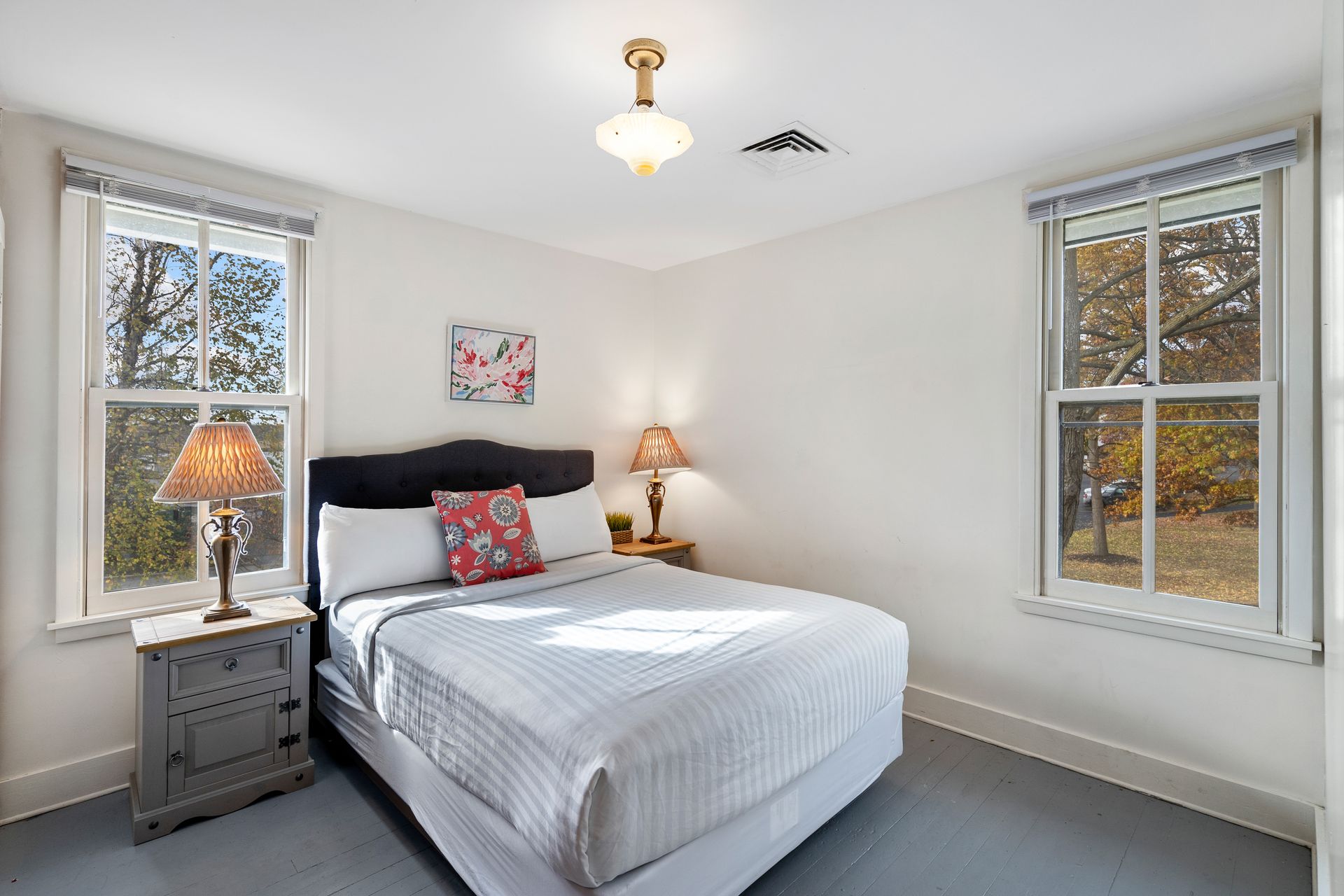 A bedroom with a king size bed and two windows