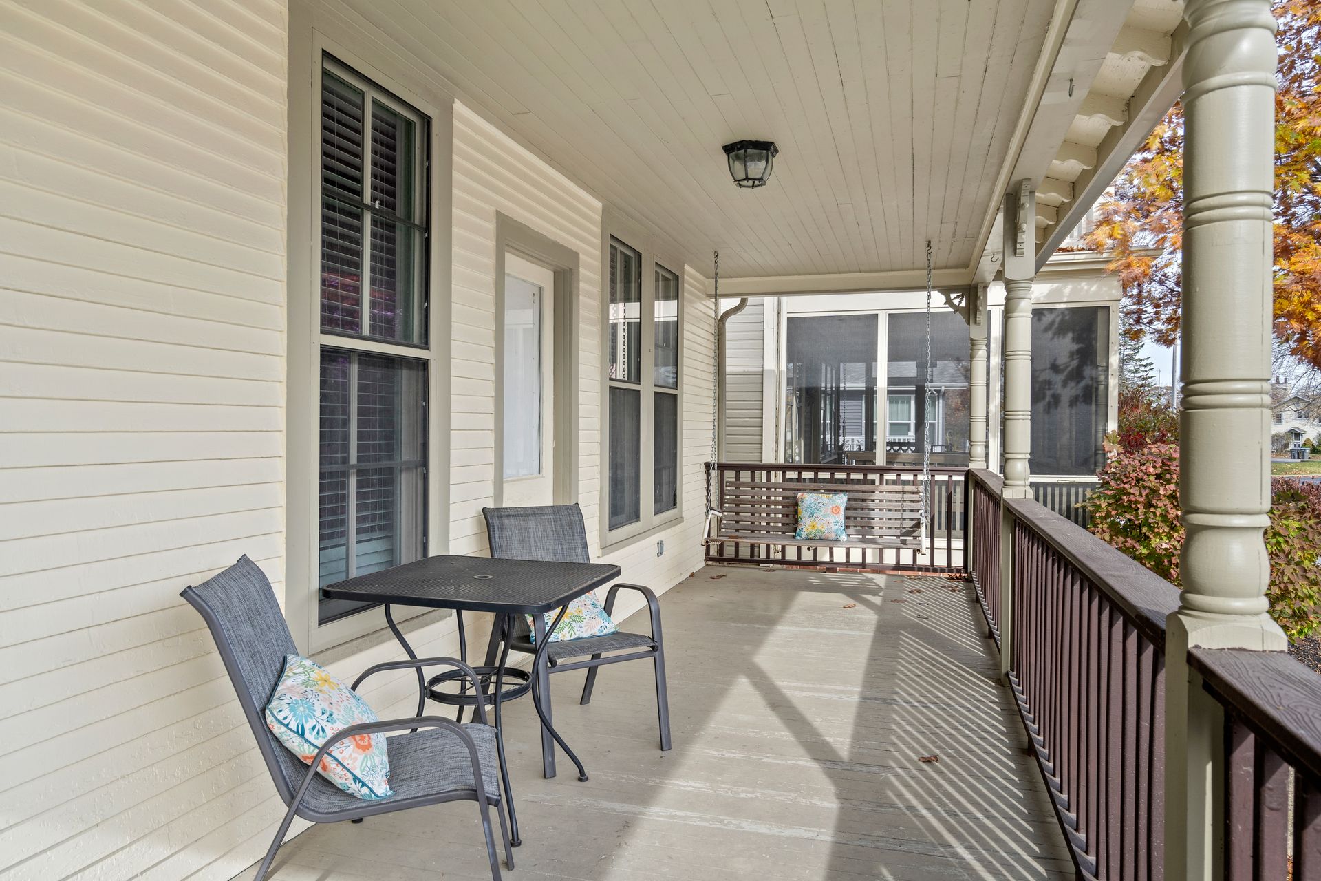 There is a porch with a table and chairs on it.