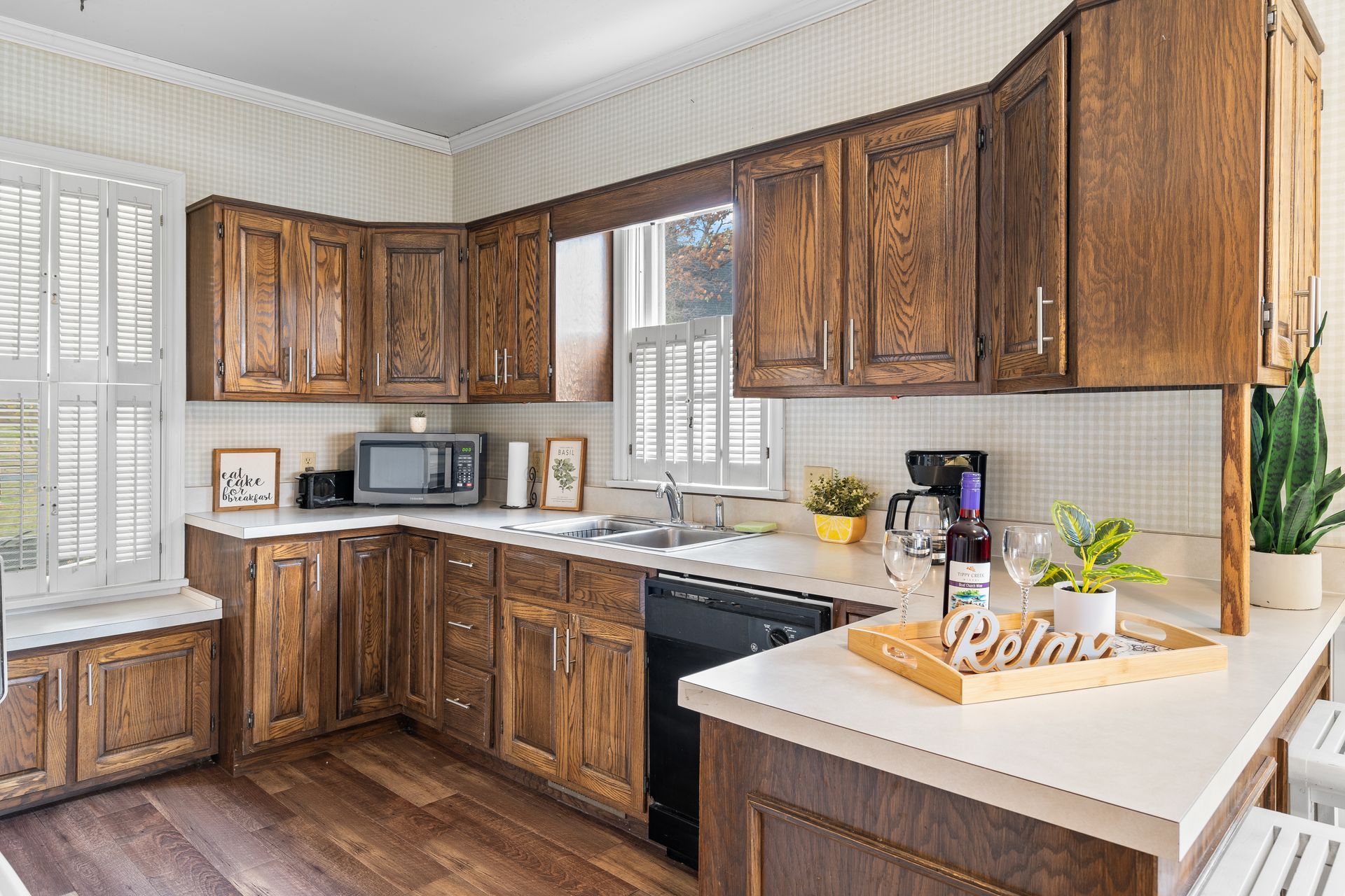 A kitchen with wooden cabinets , a sink , a microwave , and a dishwasher.