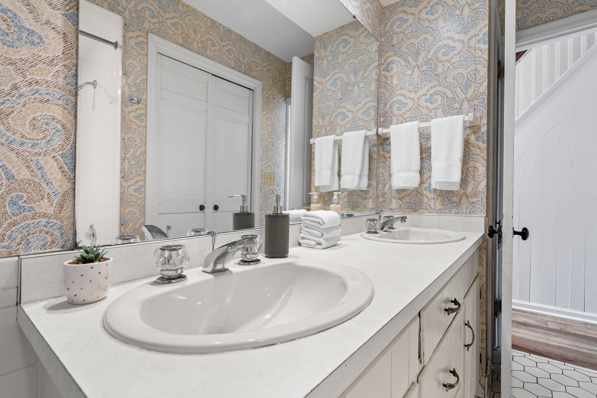 A bathroom with two sinks , a mirror and towels hanging on the wall.