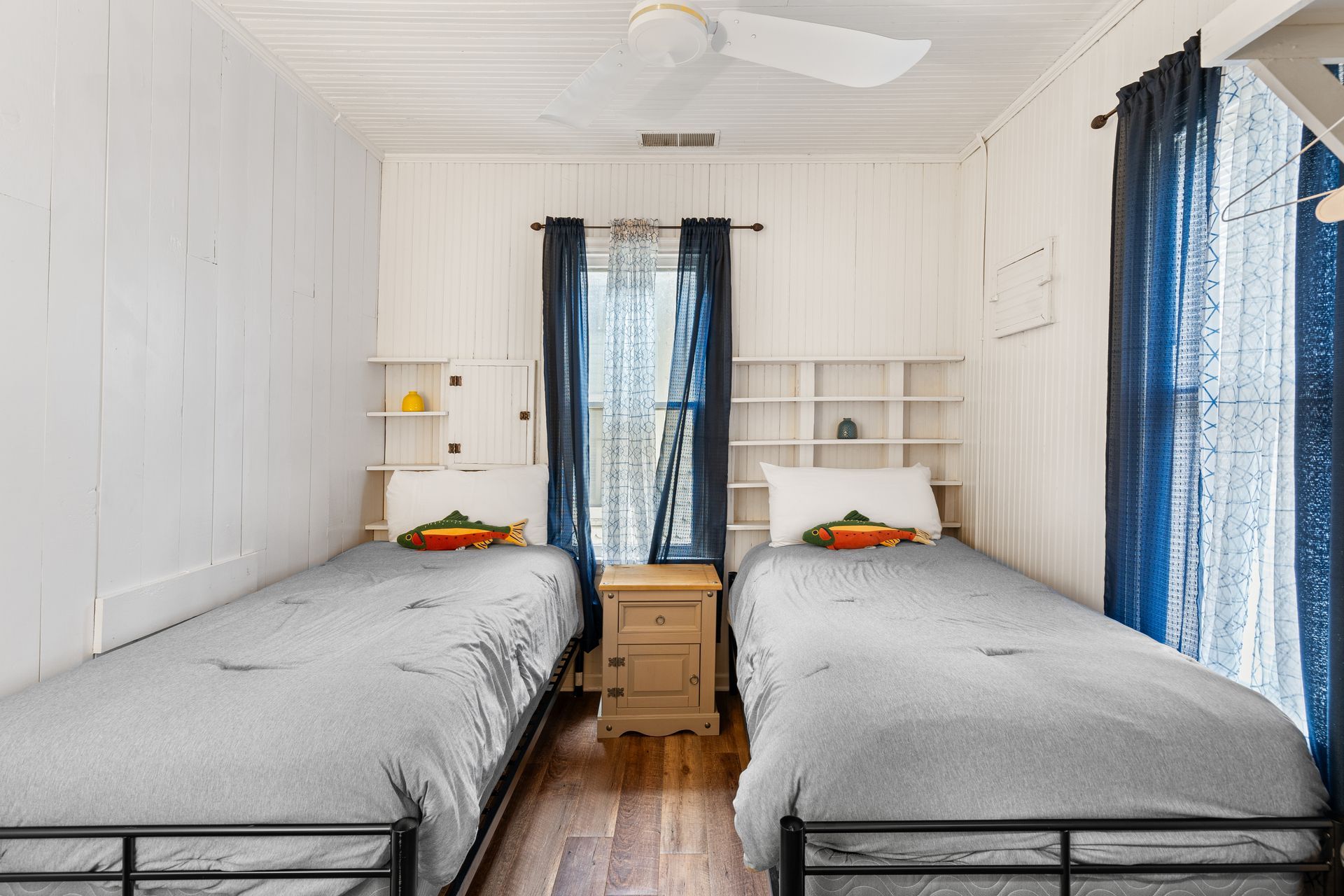 A bedroom with two twin beds and a ceiling fan.