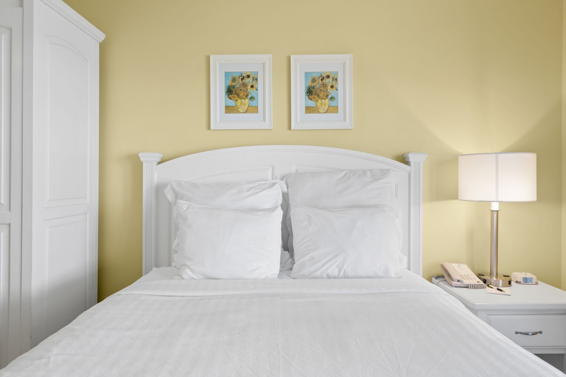A bedroom with a bed and two pictures on the wall