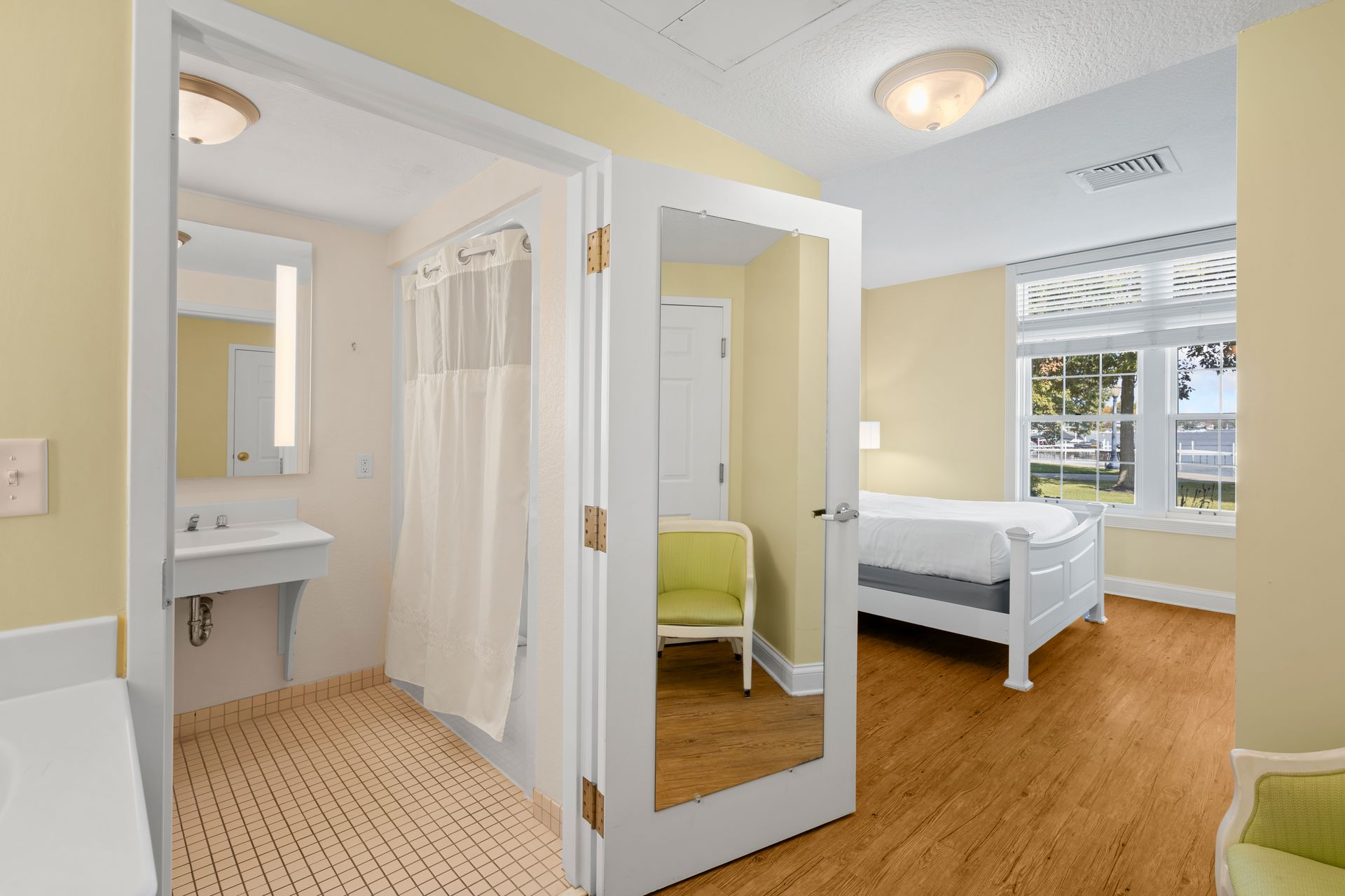 A bedroom with a bed , chair , sink and mirror