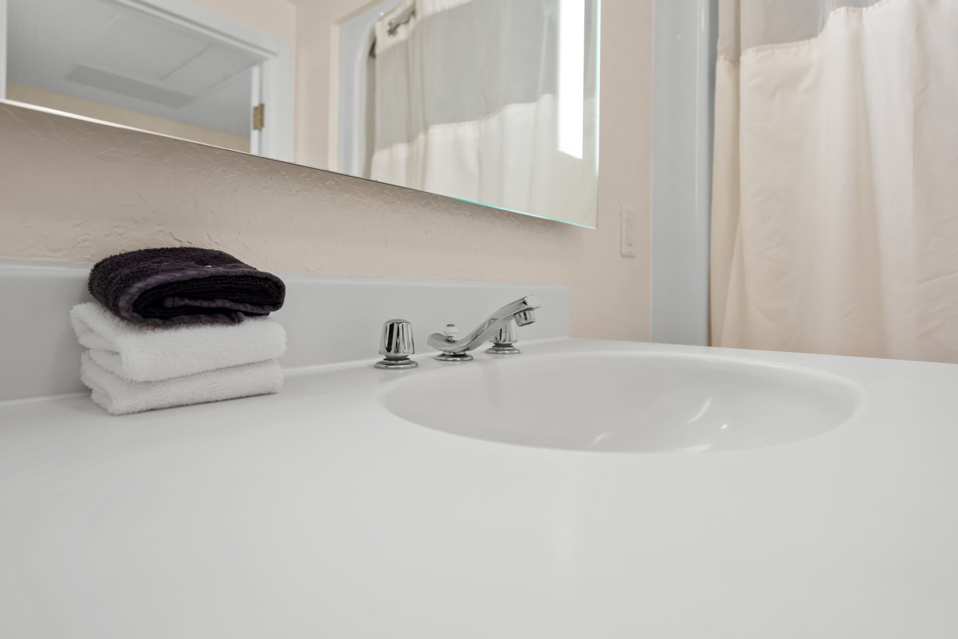 A bathroom sink with two towels stacked on top of it.