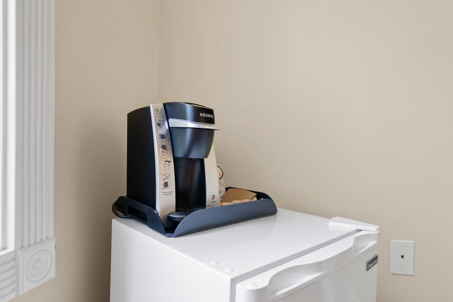 A coffee maker is sitting on top of a white refrigerator.