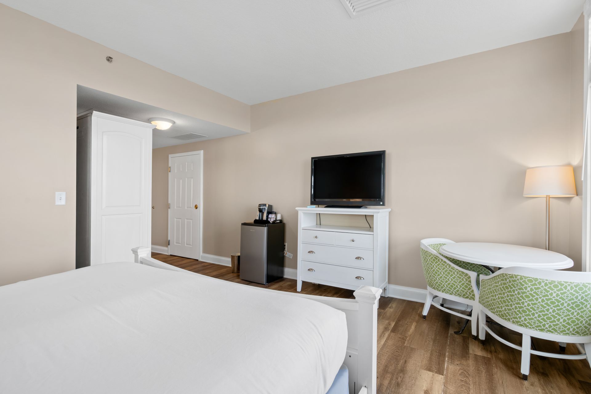 A hotel room with a bed , television , table and chairs.