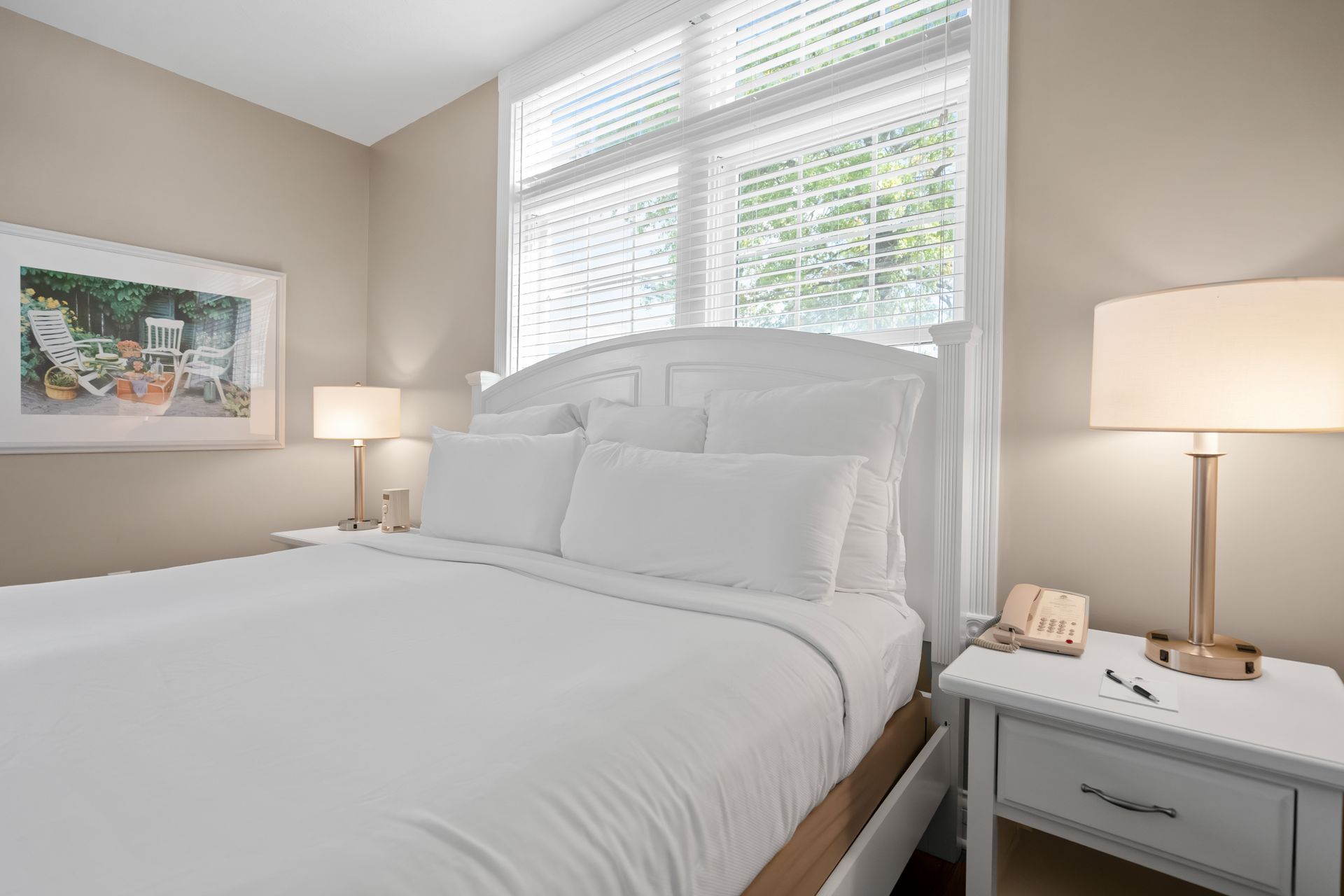 A bedroom with a bed , nightstand , lamp and window.
