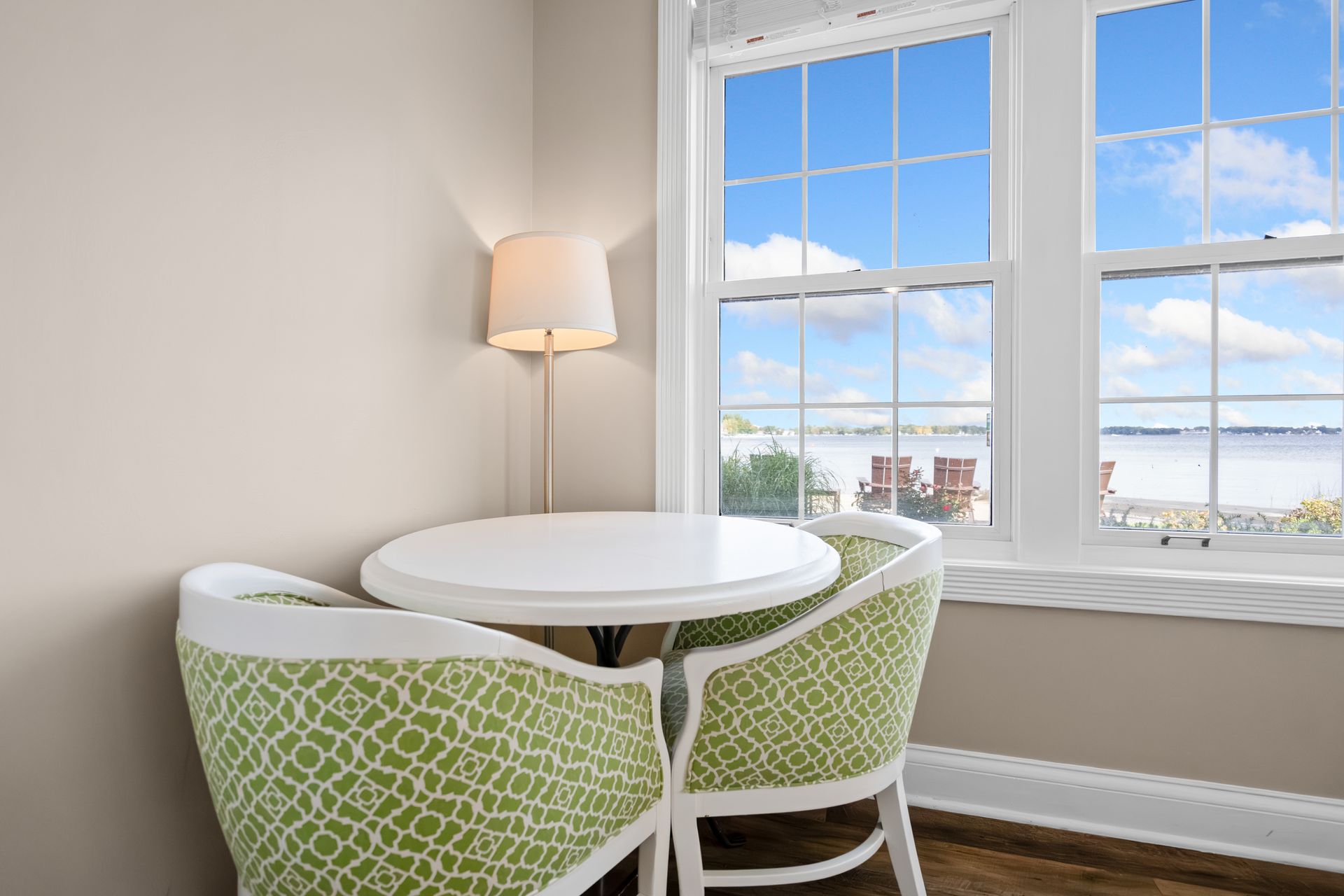 A room with a table and chairs in front of a window with a view of the ocean.