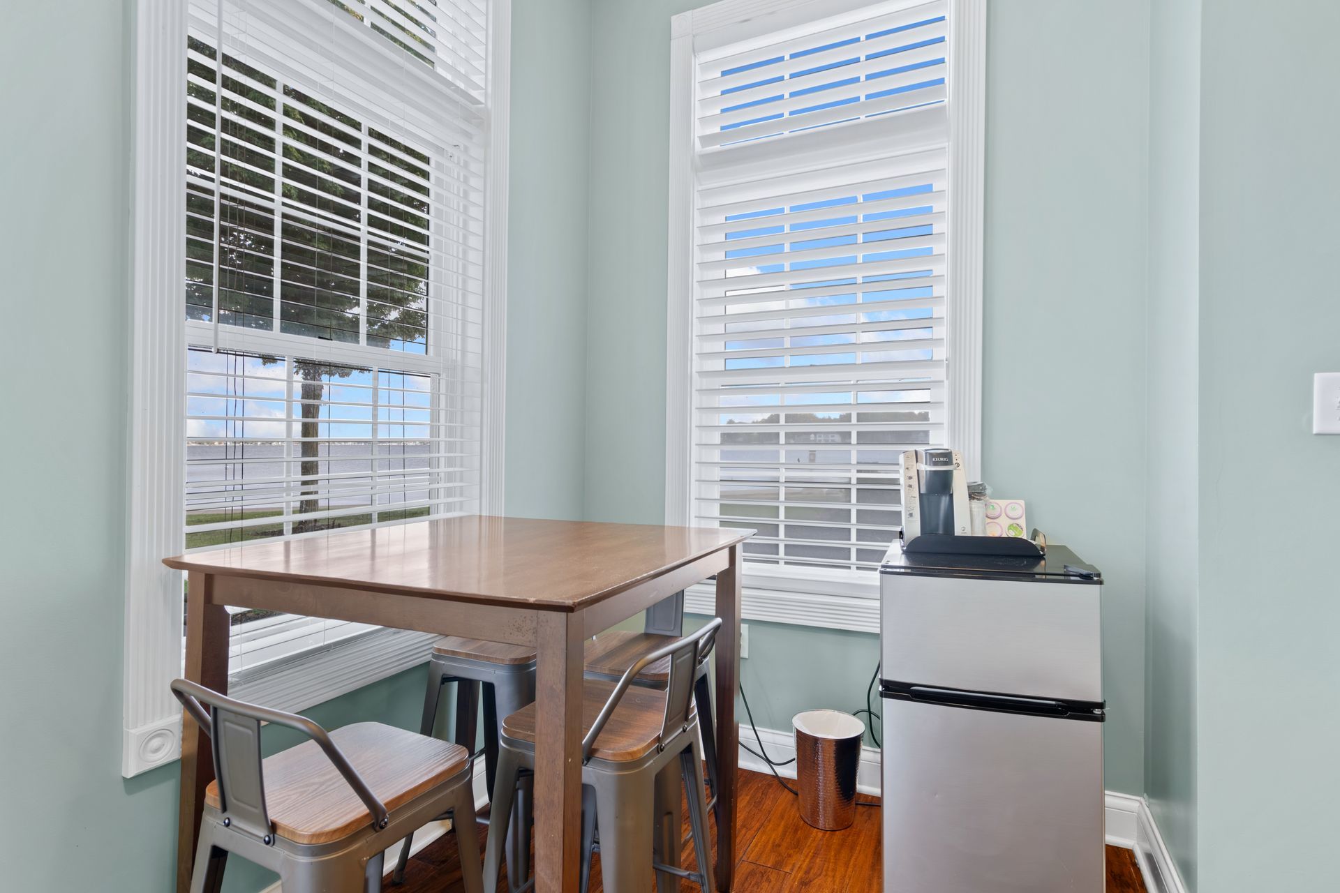 A dining room with a table and chairs and a refrigerator.