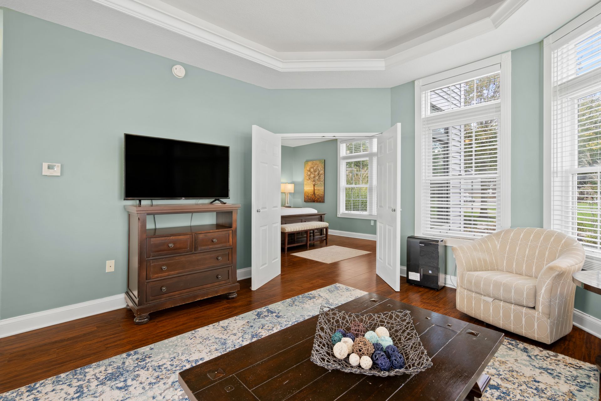 A living room with a television , coffee table , chair and dresser.