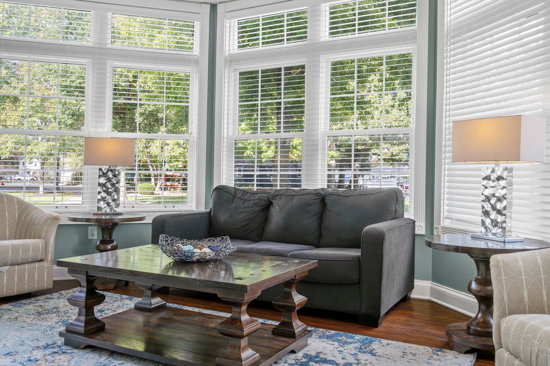 A living room with a couch , coffee table , chairs and lamps.