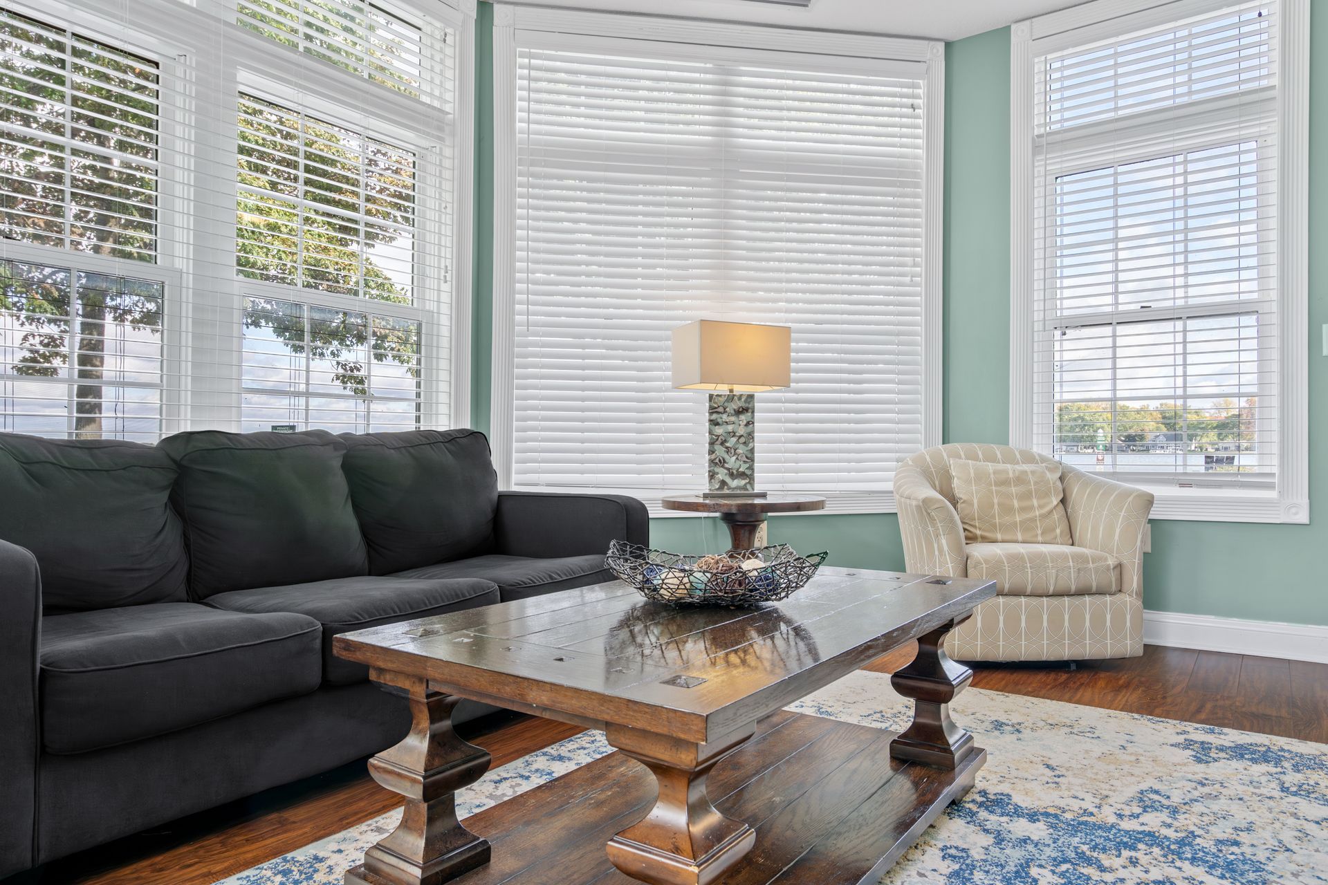 A living room with a couch , chair , coffee table and lots of windows.
